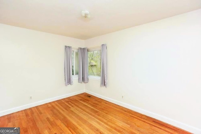 unfurnished room with baseboards and light wood-style floors