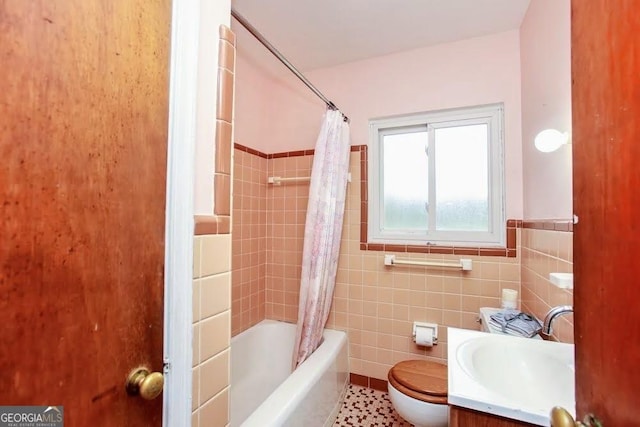 bathroom with a wainscoted wall, shower / tub combo with curtain, tile walls, toilet, and vanity