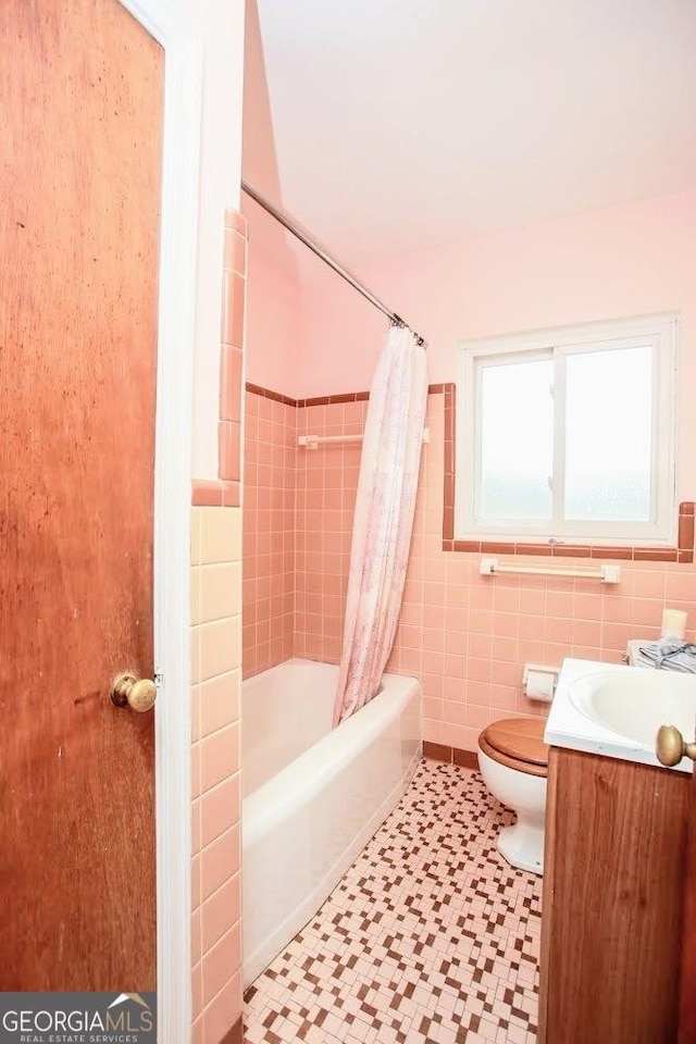 full bath with shower / tub combo, tile walls, toilet, and vanity