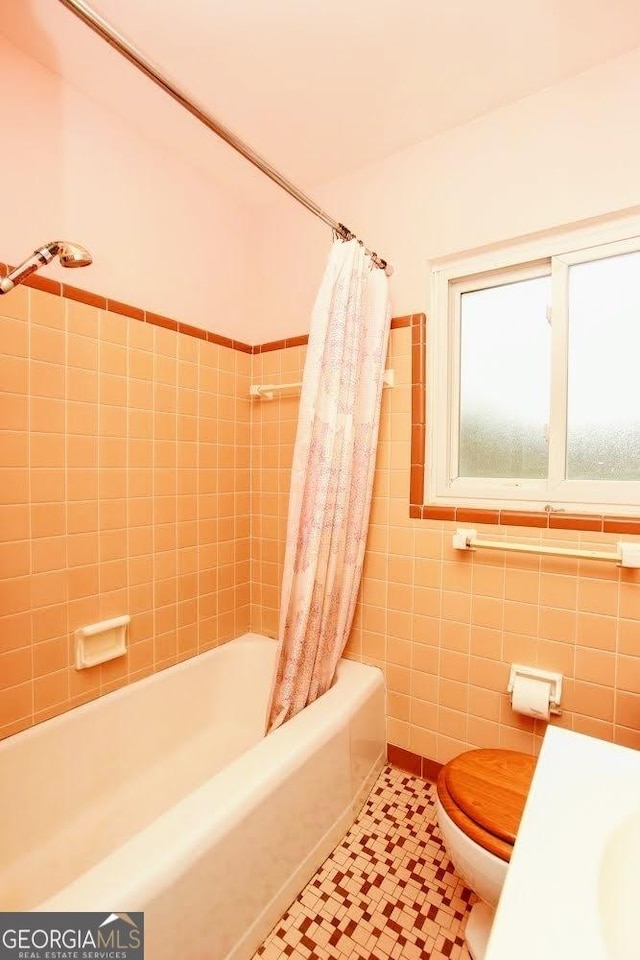 full bath featuring tile patterned floors, tile walls, toilet, and shower / bath combo with shower curtain