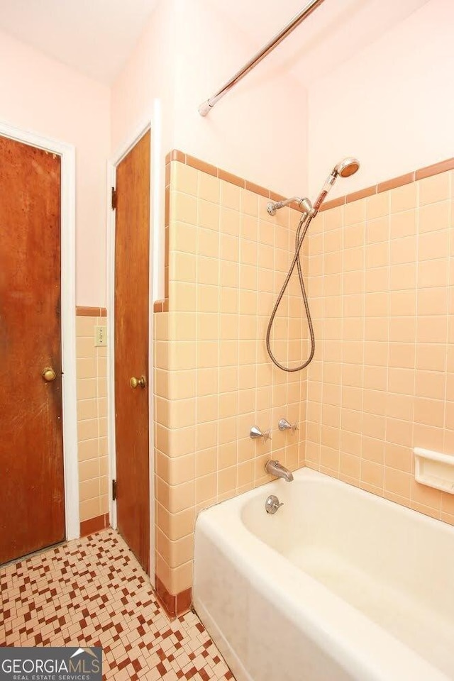 full bath featuring  shower combination, a wainscoted wall, and tile walls