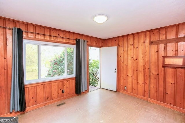 unfurnished room with visible vents, wooden walls, and tile patterned floors