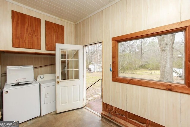 laundry area featuring washing machine and clothes dryer, cabinet space, and wooden walls