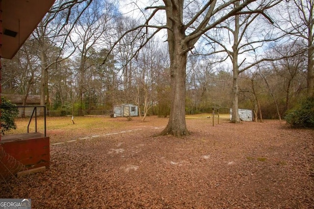 view of yard with fence, a storage unit, and an outbuilding