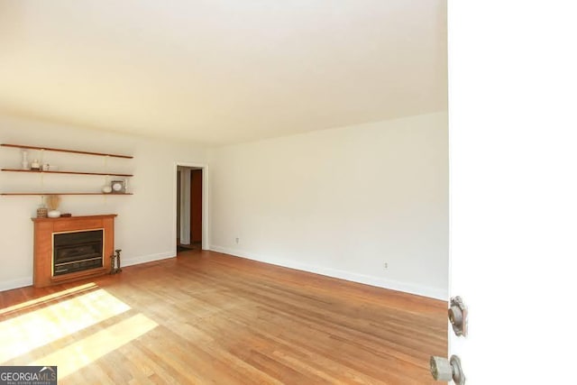 unfurnished living room featuring a fireplace, light wood-style flooring, and baseboards