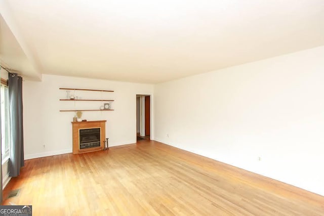 unfurnished living room with light wood-style flooring, a fireplace, and visible vents