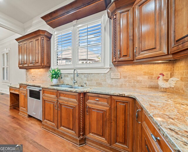 kitchen with ornamental molding, brown cabinetry, and a sink