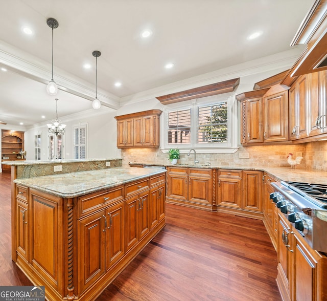 kitchen featuring light stone counters, ornamental molding, dark wood-style flooring, stainless steel gas stovetop, and a sink