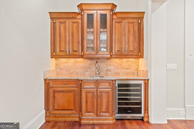 bar featuring dark wood-type flooring, beverage cooler, and a sink