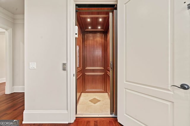 room details featuring baseboards, wood finished floors, and elevator