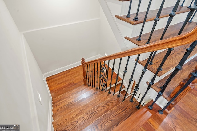 staircase featuring baseboards and wood finished floors