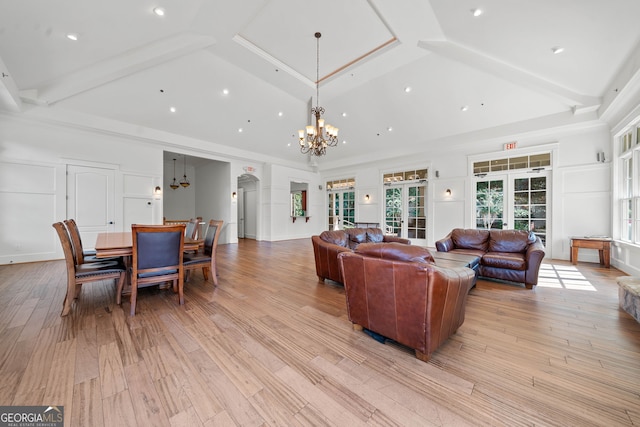 living area with light wood-style floors, arched walkways, and an inviting chandelier