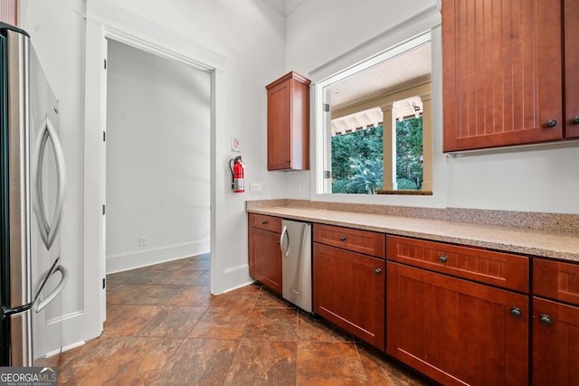 kitchen featuring refrigerator, baseboards, light countertops, freestanding refrigerator, and brown cabinets