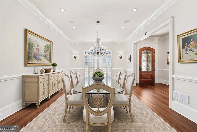 dining room featuring a chandelier, dark wood-type flooring, visible vents, and crown molding