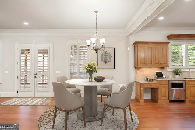 dining room with ornamental molding, french doors, a notable chandelier, and light wood finished floors