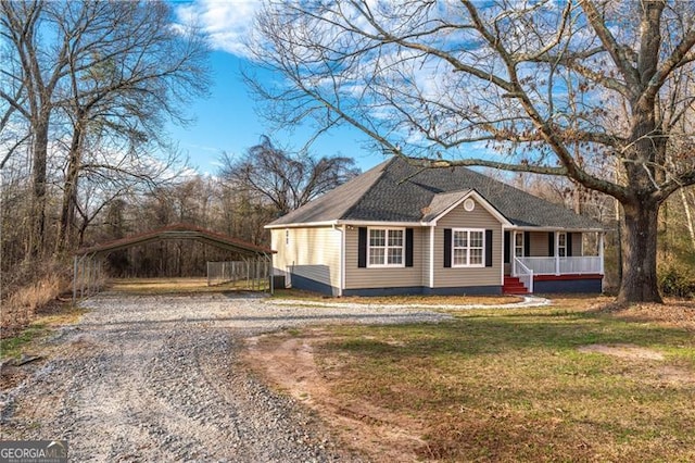 view of side of home featuring a detached carport, covered porch, a lawn, and gravel driveway