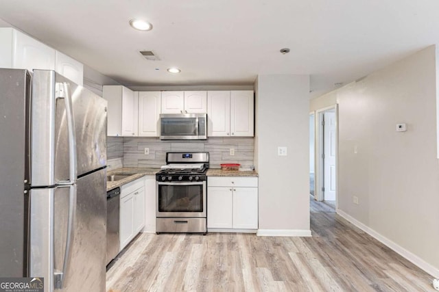 kitchen with stainless steel appliances, white cabinetry, baseboards, light wood-type flooring, and tasteful backsplash