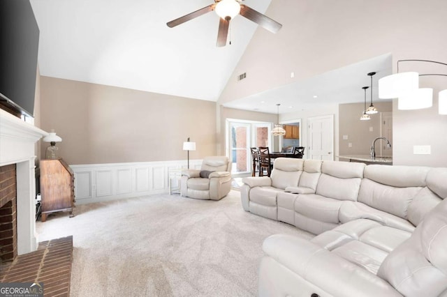 living room with visible vents, a wainscoted wall, carpet flooring, a fireplace, and high vaulted ceiling