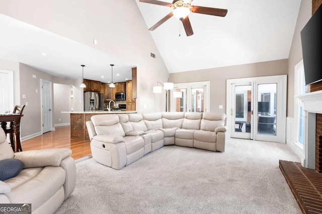 living area featuring baseboards, visible vents, high vaulted ceiling, a fireplace, and ceiling fan