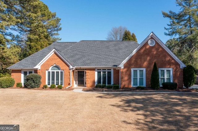 view of front facade with brick siding and roof with shingles