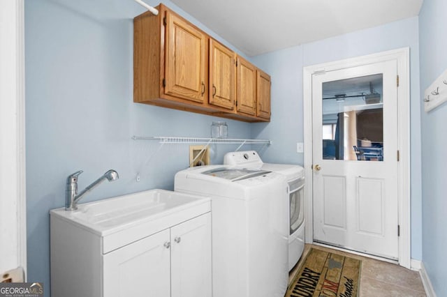 laundry area with cabinet space, washing machine and dryer, baseboards, and a sink