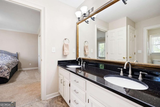 ensuite bathroom with a sink, baseboards, and plenty of natural light