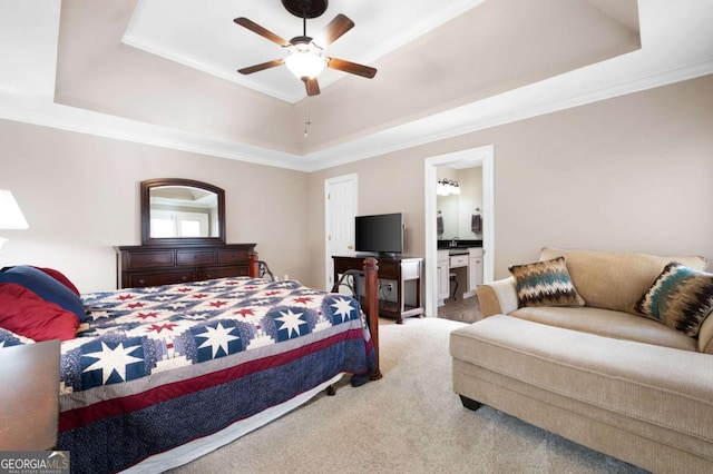 carpeted bedroom with ensuite bathroom, a ceiling fan, crown molding, and a tray ceiling