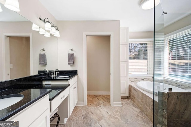 full bathroom featuring double vanity, baseboards, a garden tub, and a sink