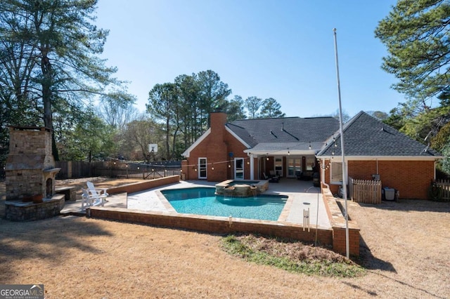 view of pool with a patio area, an outdoor fireplace, a fenced backyard, and a pool with connected hot tub