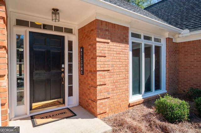 property entrance with brick siding and a shingled roof