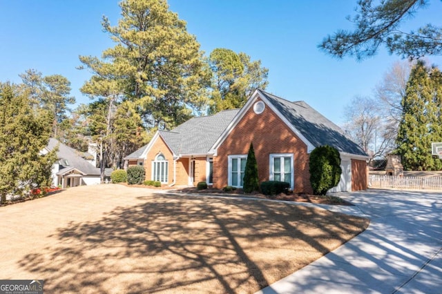 view of front of home featuring concrete driveway, fence, and brick siding