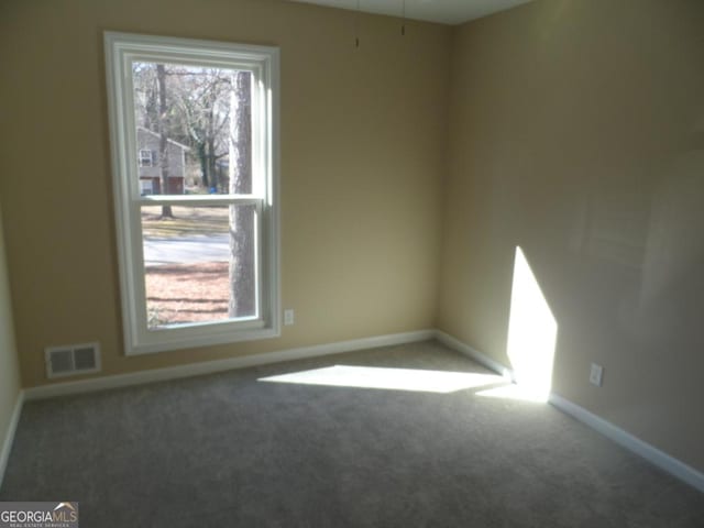 carpeted empty room with visible vents and baseboards