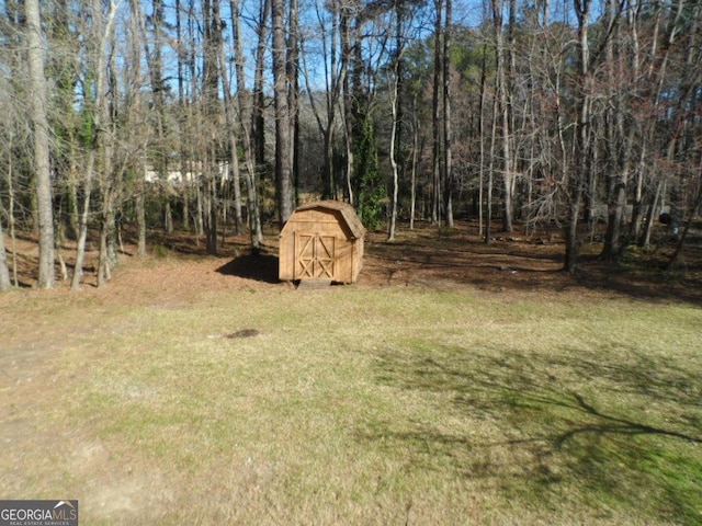 view of yard featuring an outbuilding, a shed, and a view of trees