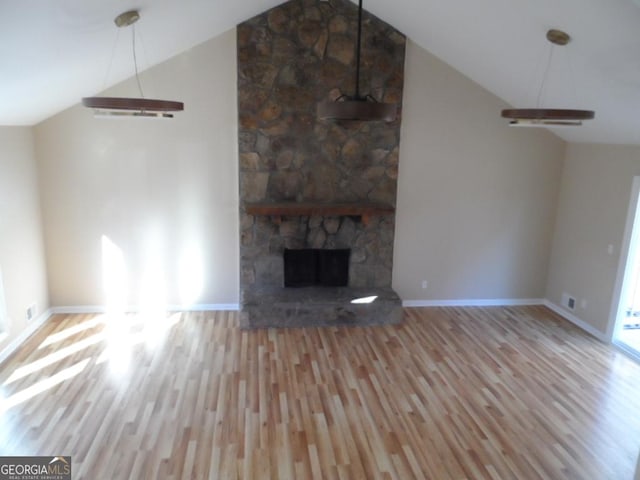 unfurnished living room featuring high vaulted ceiling, a stone fireplace, baseboards, and wood finished floors