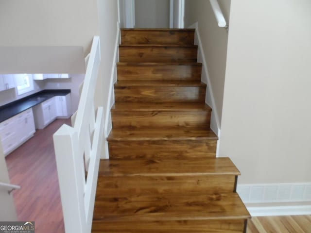 stairway featuring visible vents and wood finished floors