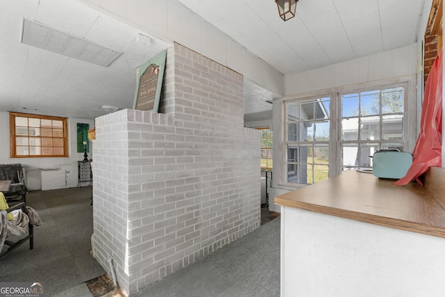 interior space with carpet flooring and brick wall