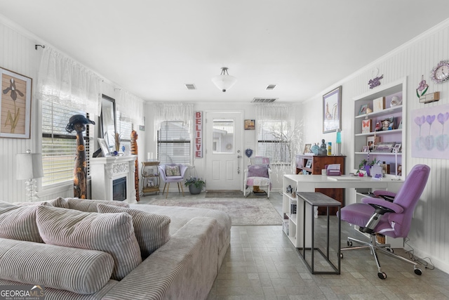 living room featuring crown molding, a fireplace, visible vents, and stone finish flooring