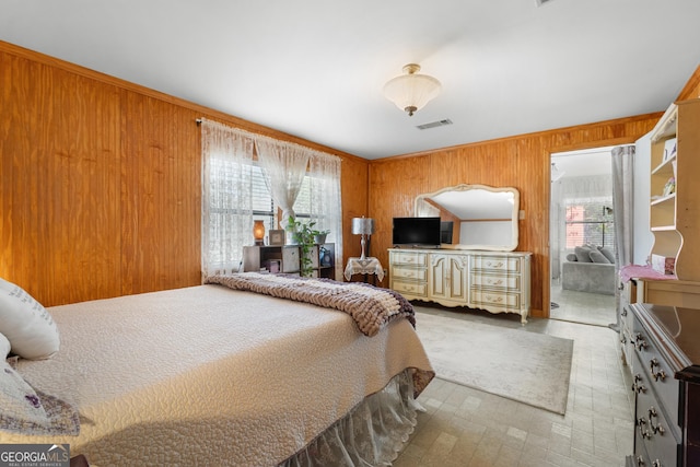 bedroom featuring visible vents, multiple windows, and wood walls