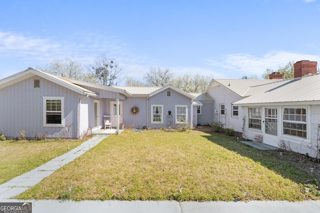 exterior space with metal roof and a yard
