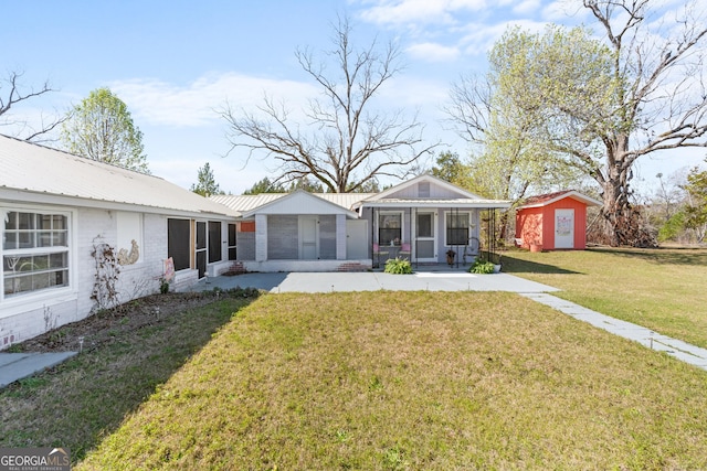 back of property with a sunroom, an outdoor structure, a storage shed, a lawn, and metal roof