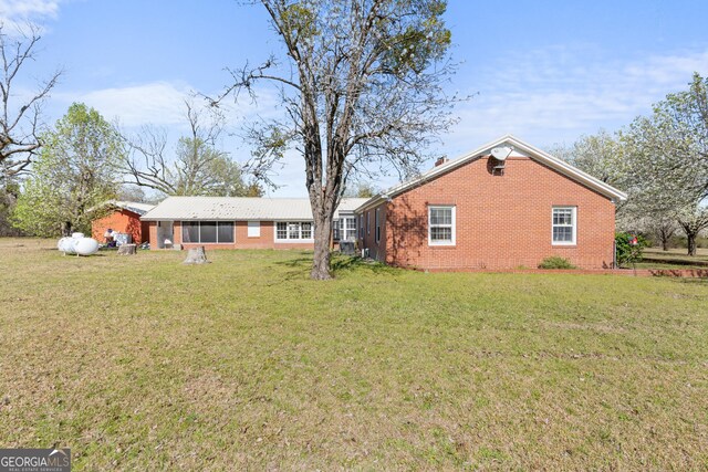 back of property with a yard and brick siding