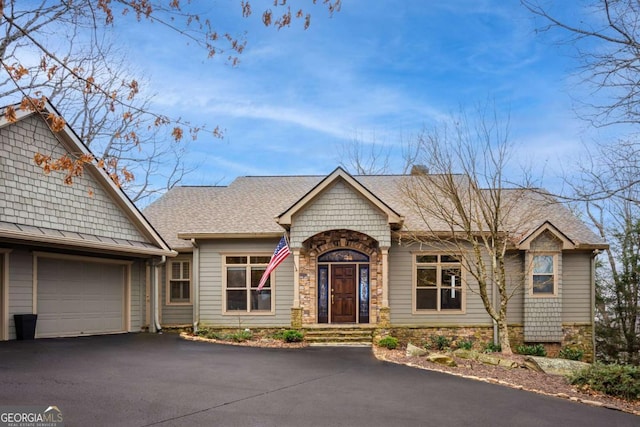 single story home with aphalt driveway, stone siding, a shingled roof, and an attached garage