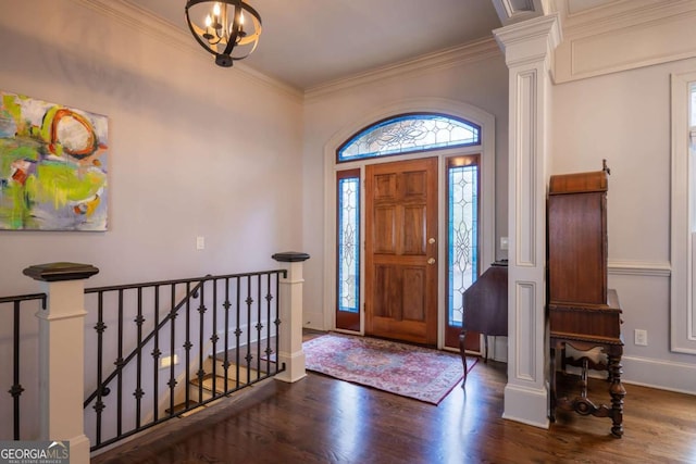 entrance foyer featuring a chandelier, wood finished floors, baseboards, ornamental molding, and decorative columns