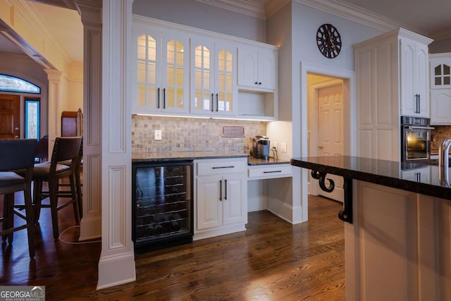 132 Sanderlin Mountain Dr S, Big Canoe, GA 30143 - bar area featuring wine cooler, black oven, crown molding, dark wood-style floors, and decorative backsplash