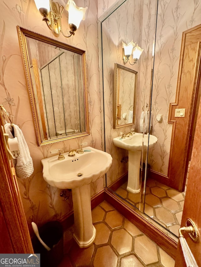 bathroom featuring a sink, a notable chandelier, baseboards, and wallpapered walls