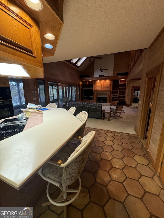 kitchen featuring a textured ceiling, carpet floors, a fireplace, vaulted ceiling, and black appliances