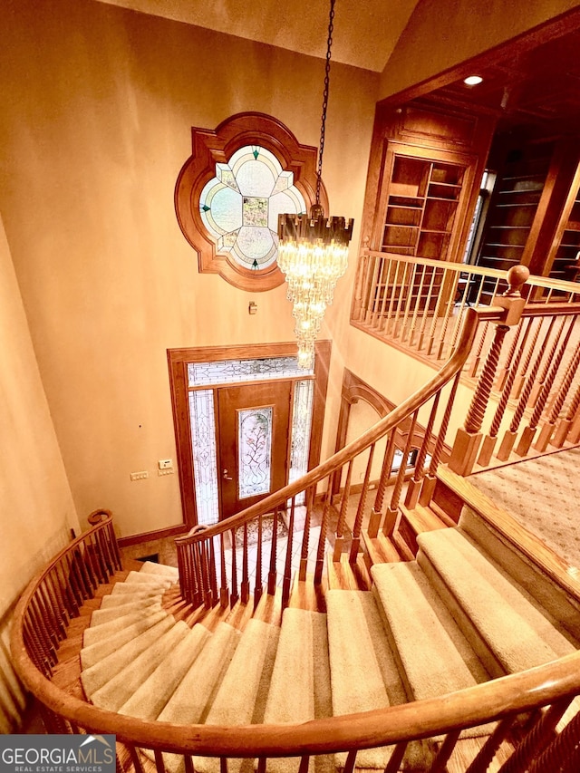 stairway featuring baseboards, a high ceiling, and a notable chandelier