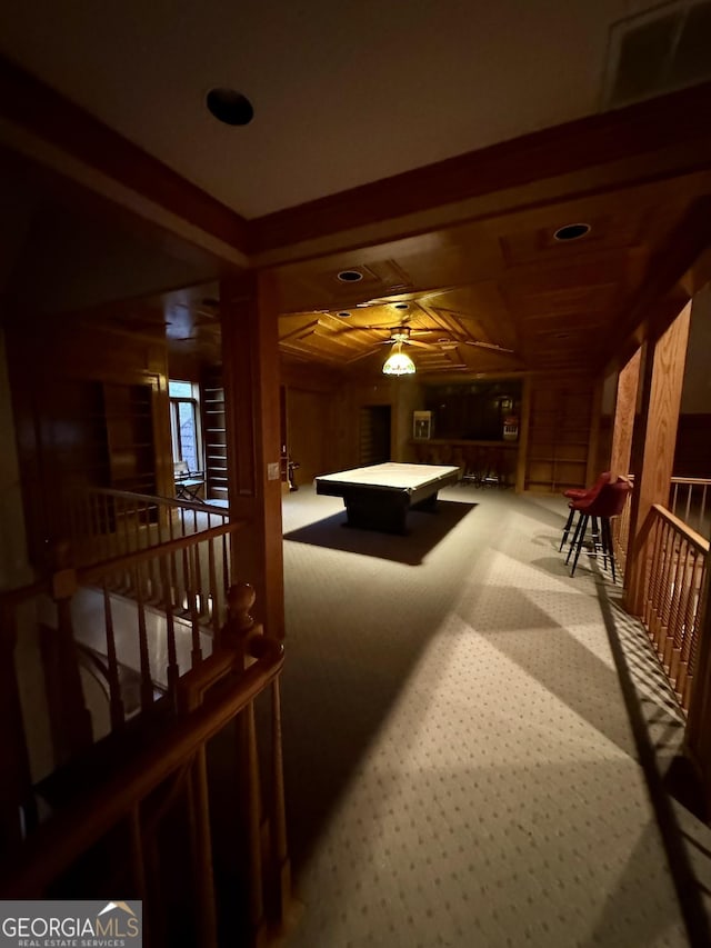 recreation room with carpet floors, wooden walls, and beamed ceiling