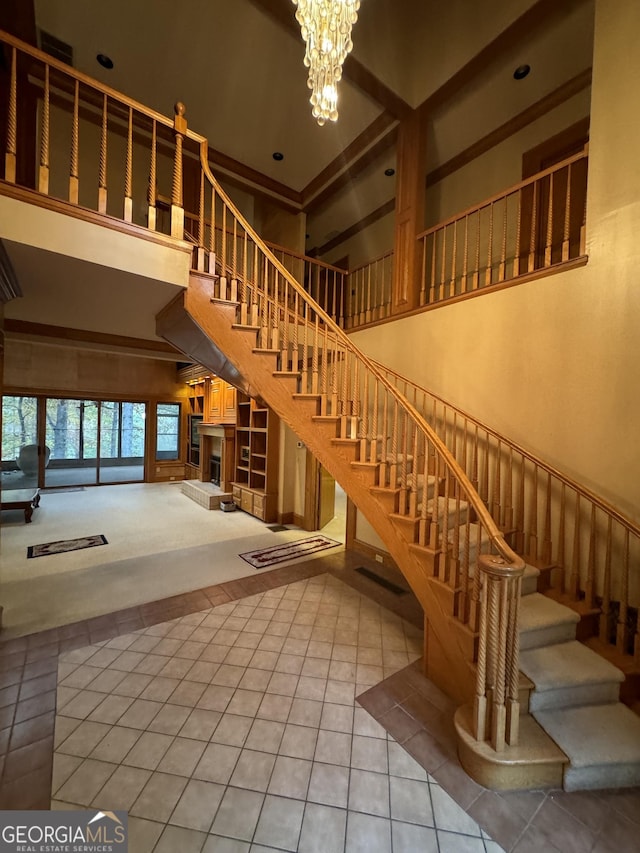 interior space featuring a chandelier, a fireplace with raised hearth, a high ceiling, and tile patterned floors