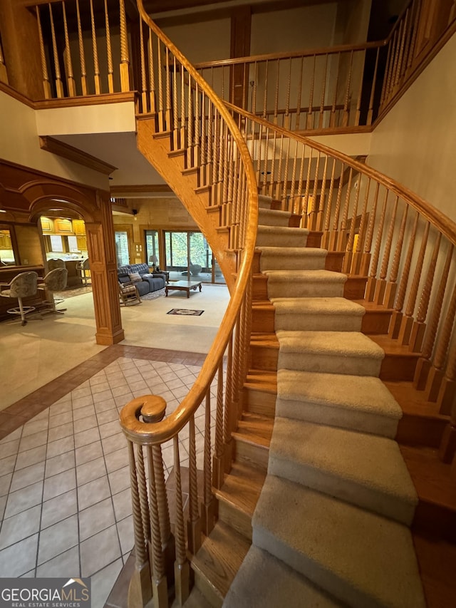 staircase featuring a towering ceiling and tile patterned flooring